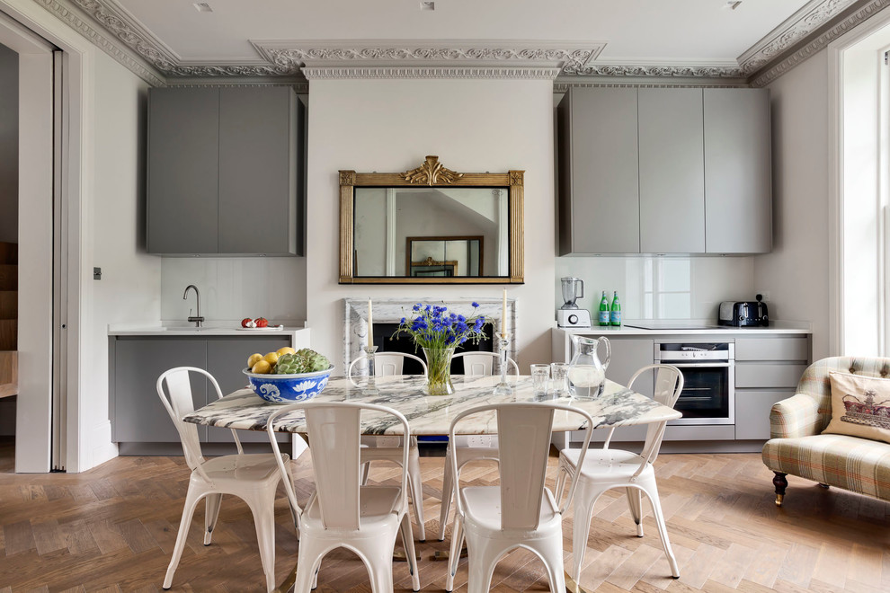 Mittelgroße Stilmix Wohnküche mit braunem Holzboden, grauer Wandfarbe, Kamin, Kaminumrandung aus Stein und braunem Boden in London