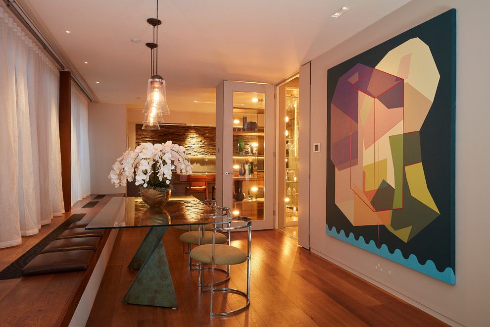 Réalisation d'une salle à manger design avec un mur blanc, un sol en bois brun et un sol marron.