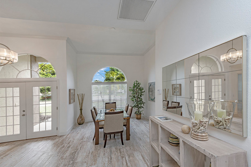 Foto di una piccola sala da pranzo aperta verso la cucina classica con pareti bianche, pavimento in laminato, nessun camino e pavimento grigio