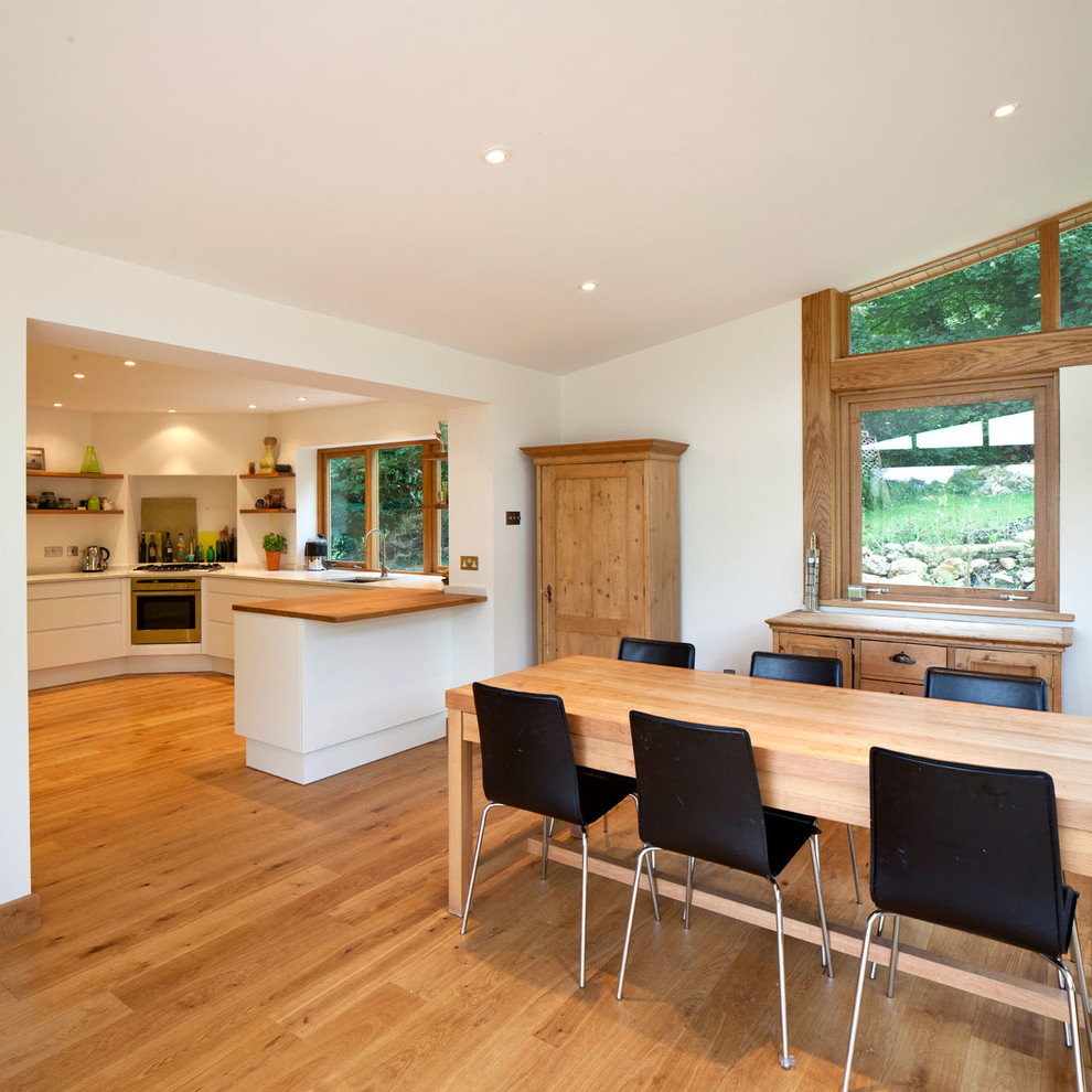 Esempio di una sala da pranzo aperta verso la cucina design con pareti bianche e pavimento in legno massello medio