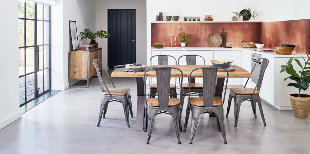 Cette image montre une salle à manger ouverte sur la cuisine urbaine de taille moyenne avec un mur blanc, sol en béton ciré et un sol gris.