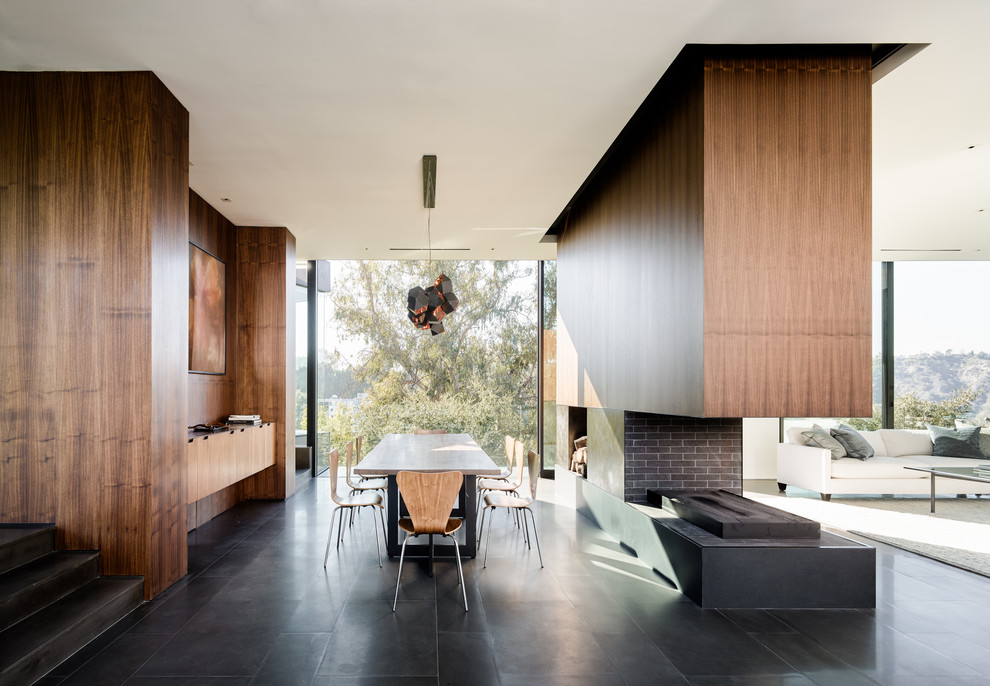 Источник вдохновения для домашнего уюта: столовая в стиле модернизм с коричневыми стенами, двусторонним камином, фасадом камина из кирпича и черным полом