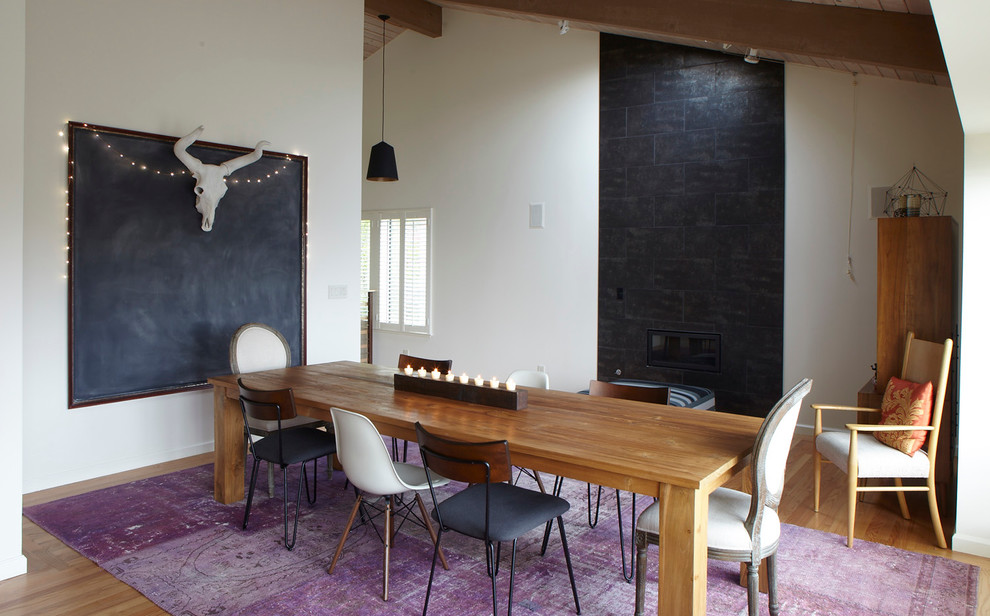 Immagine di una sala da pranzo minimal chiusa e di medie dimensioni con pareti bianche, pavimento in bambù, camino sospeso, cornice del camino in cemento e pavimento marrone