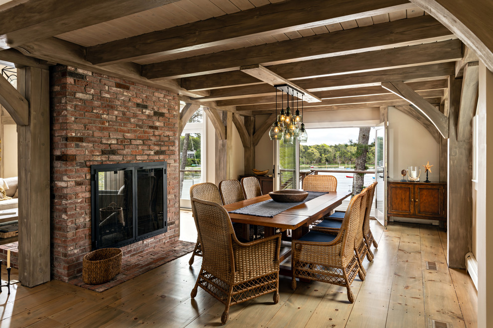 This is an example of a nautical enclosed dining room in Boston with beige walls, light hardwood flooring, a two-sided fireplace and a brick fireplace surround.