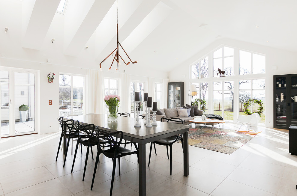 Стильный дизайн: огромная гостиная-столовая в скандинавском стиле с белыми стенами, полом из известняка и бежевым полом без камина - последний тренд