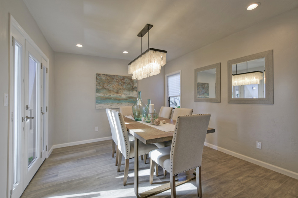 This is an example of a medium sized contemporary open plan dining room in San Diego with grey walls, light hardwood flooring, a standard fireplace, a stone fireplace surround and grey floors.