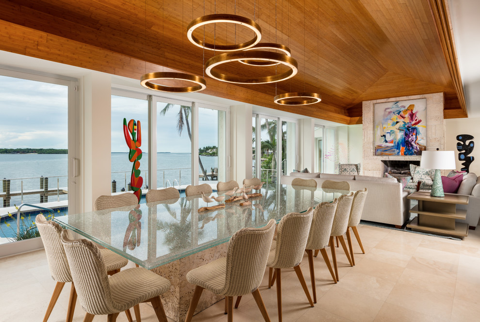 World-inspired open plan dining room in Miami with beige walls, beige floors and feature lighting.