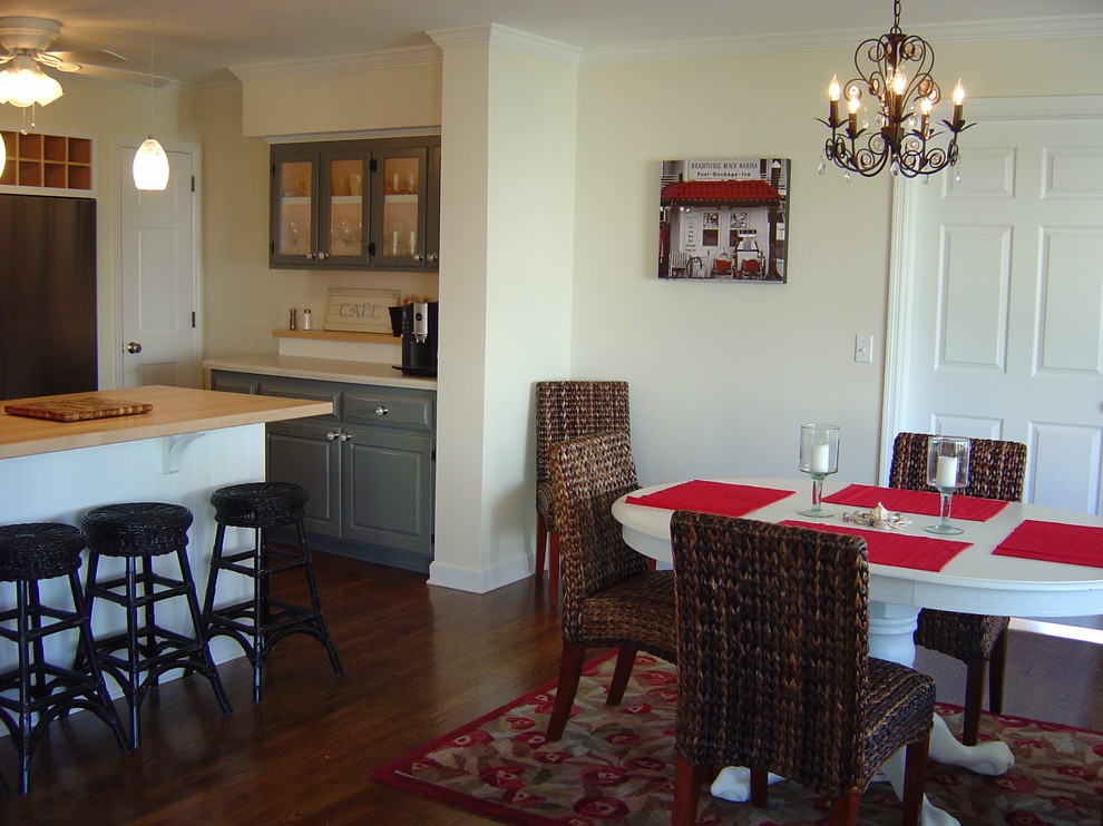 Aménagement d'une salle à manger ouverte sur la cuisine bord de mer de taille moyenne avec un mur beige et parquet foncé.