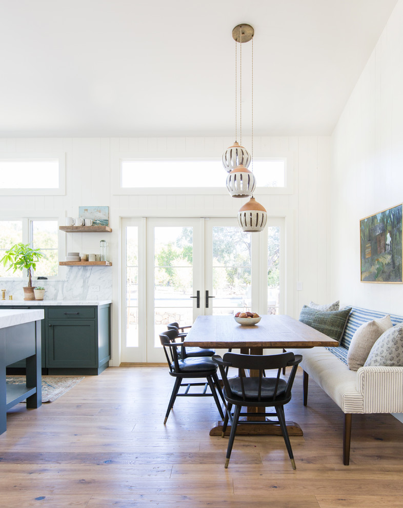 Ispirazione per una sala da pranzo aperta verso la cucina costiera con pareti bianche, pavimento in legno massello medio e pavimento marrone