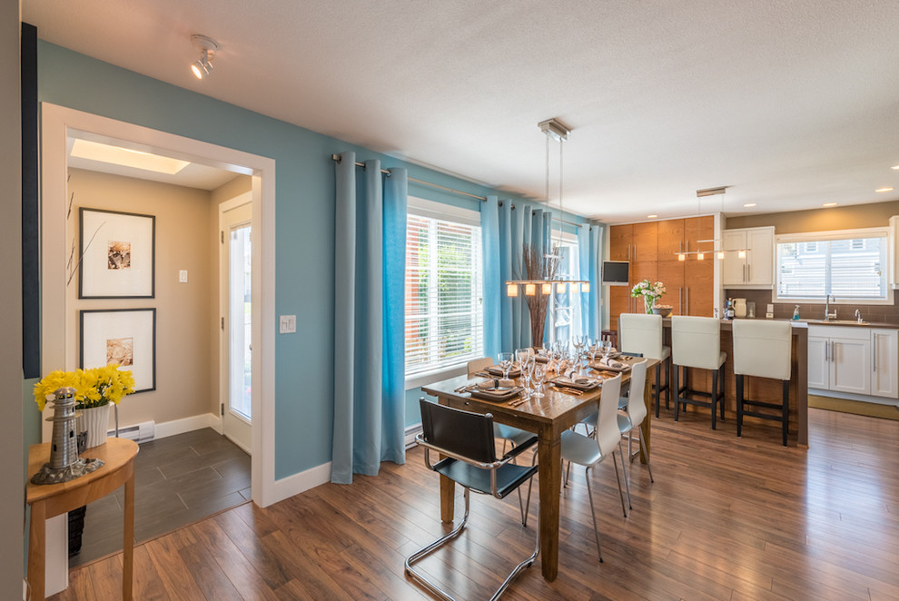 На фото: кухня-столовая среднего размера в современном стиле с синими стенами, полом из ламината и коричневым полом