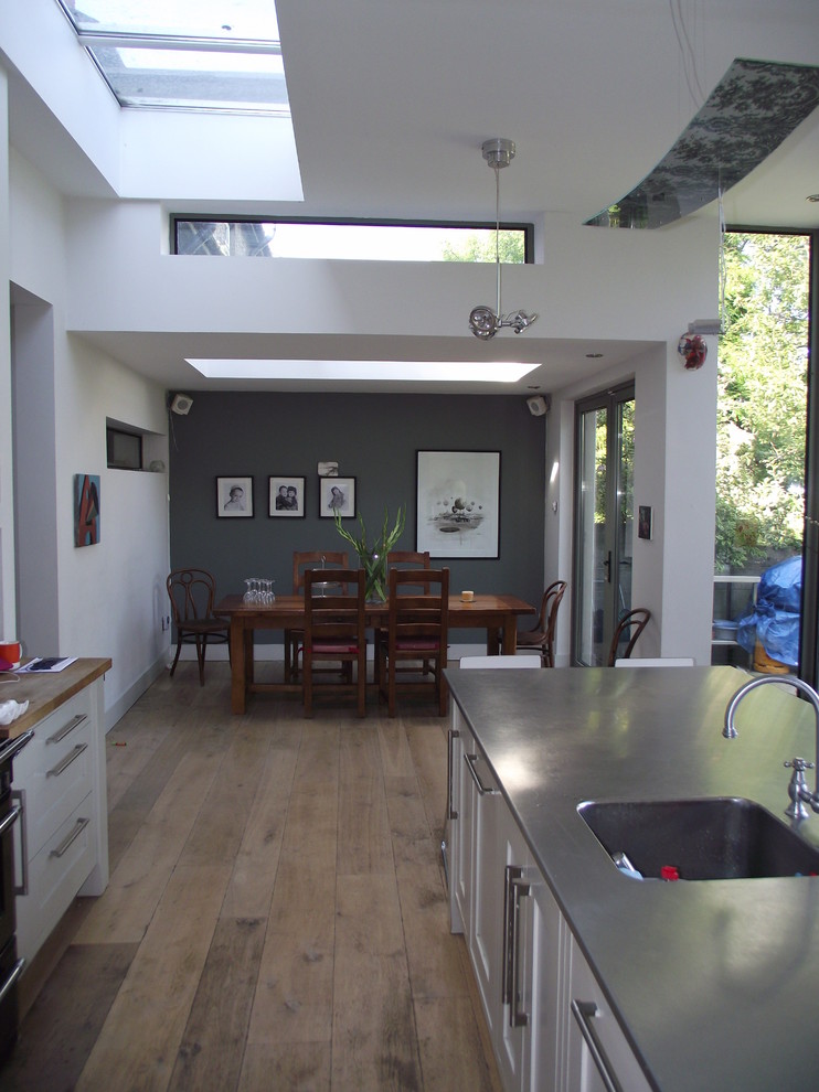 Idee per una sala da pranzo aperta verso la cucina moderna di medie dimensioni con pareti grigie, parquet chiaro e nessun camino