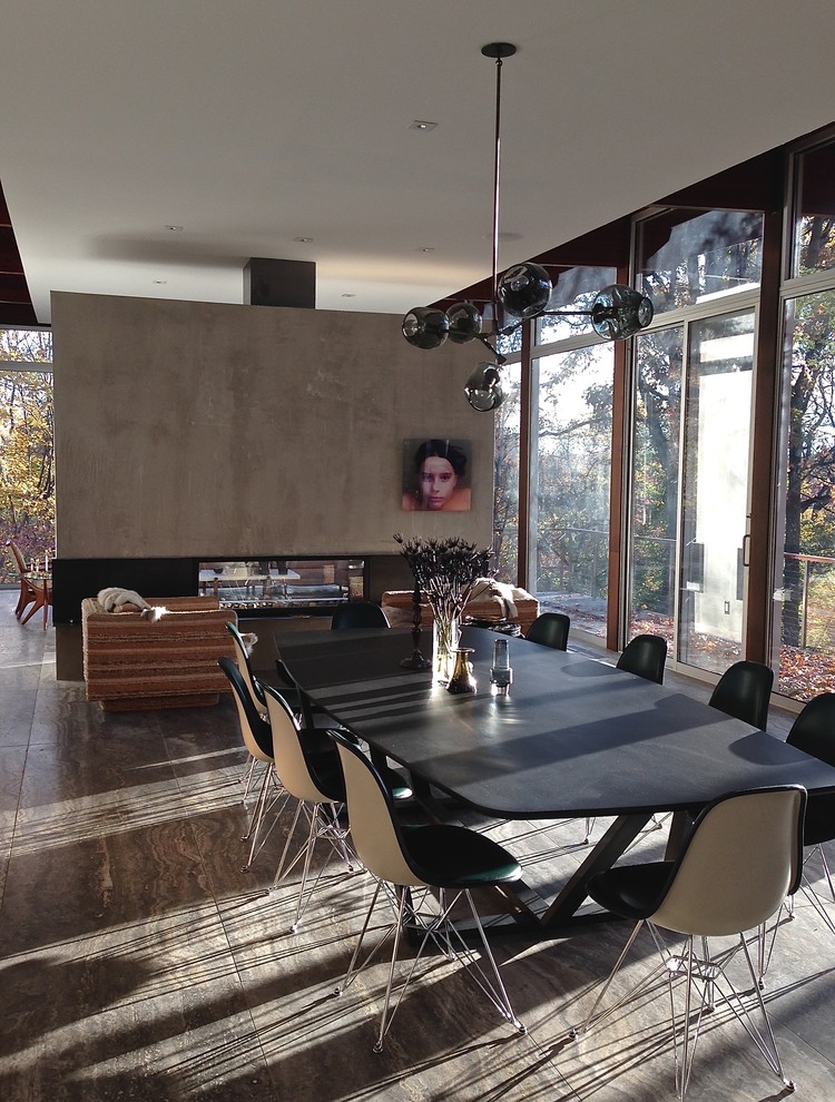 Cette image montre une très grande salle à manger ouverte sur le salon design avec un mur blanc, un sol en travertin, une cheminée double-face, un manteau de cheminée en métal et un sol gris.