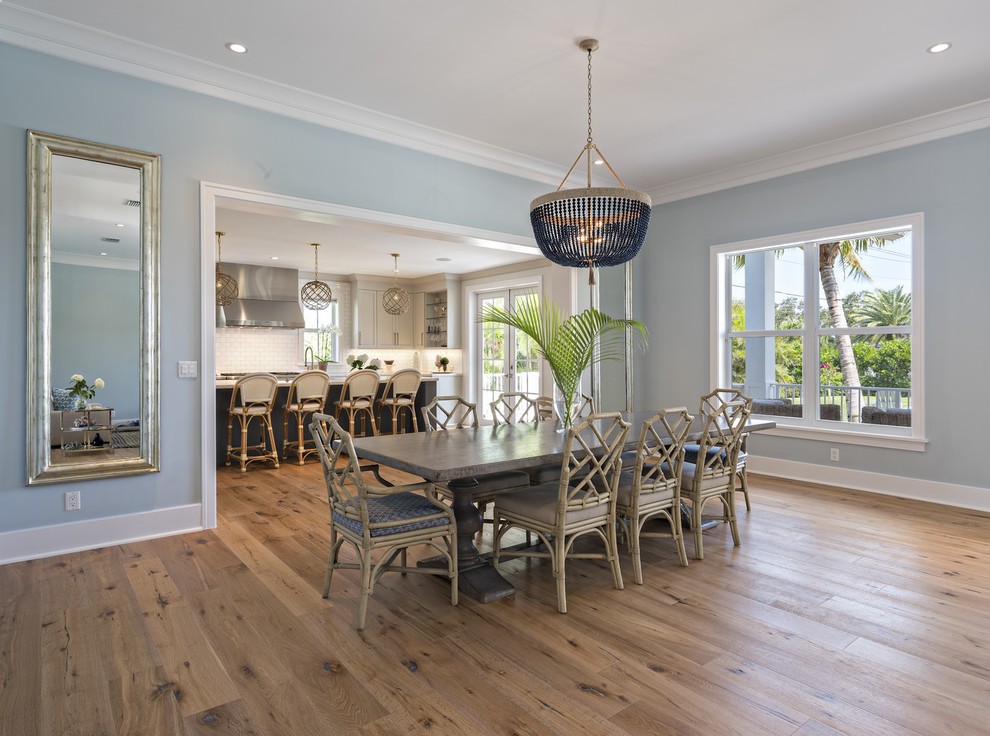 Immagine di una grande sala da pranzo aperta verso il soggiorno stile marinaro con pareti blu e pavimento in legno massello medio