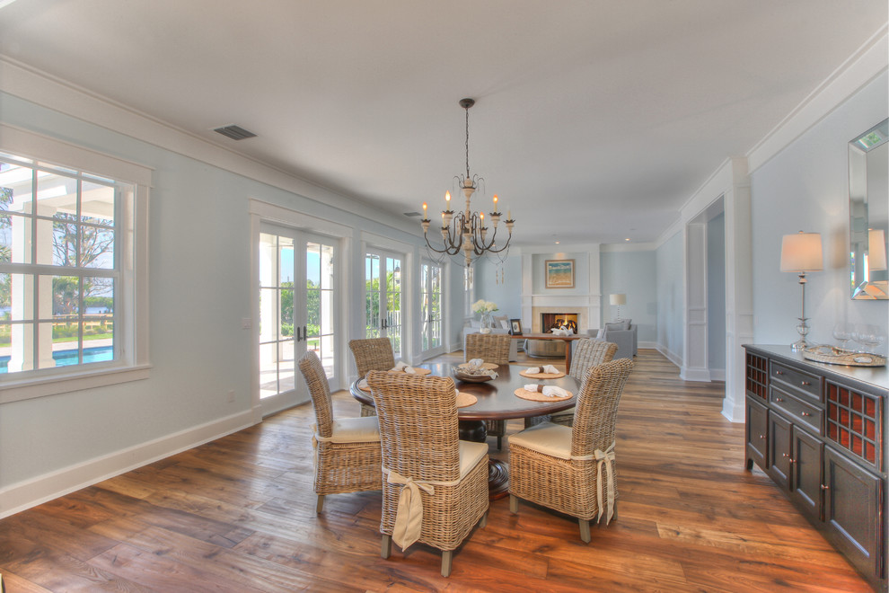 Foto di una grande sala da pranzo aperta verso il soggiorno costiera con pareti blu e pavimento in legno massello medio