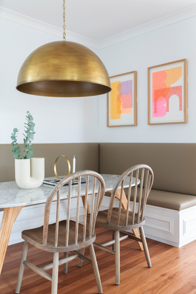 Idée de décoration pour une salle à manger tradition de taille moyenne avec un sol en bois brun, une banquette d'angle, un mur blanc et un sol marron.