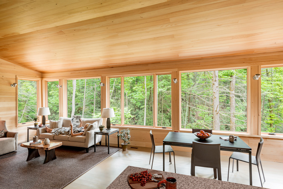 Cette image montre une petite salle à manger ouverte sur le salon minimaliste avec un mur beige, un sol en bois brun, une cheminée standard, un manteau de cheminée en bois, un sol marron et éclairage.