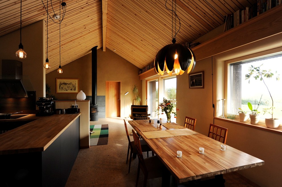 Свежая идея для дизайна: гостиная-столовая в современном стиле с желтыми стенами, печью-буржуйкой и коричневым полом - отличное фото интерьера