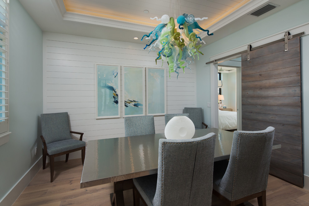 Photo of a coastal enclosed dining room in Miami with blue walls, light hardwood flooring, no fireplace and beige floors.