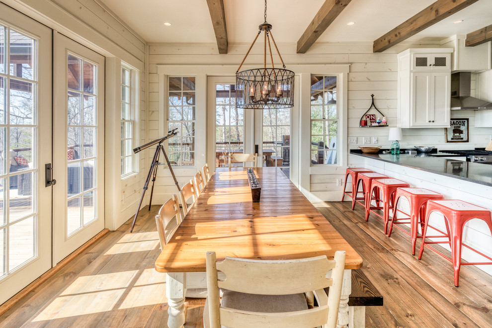 Foto di una sala da pranzo aperta verso la cucina country con pareti bianche, pavimento in legno massello medio e pavimento marrone