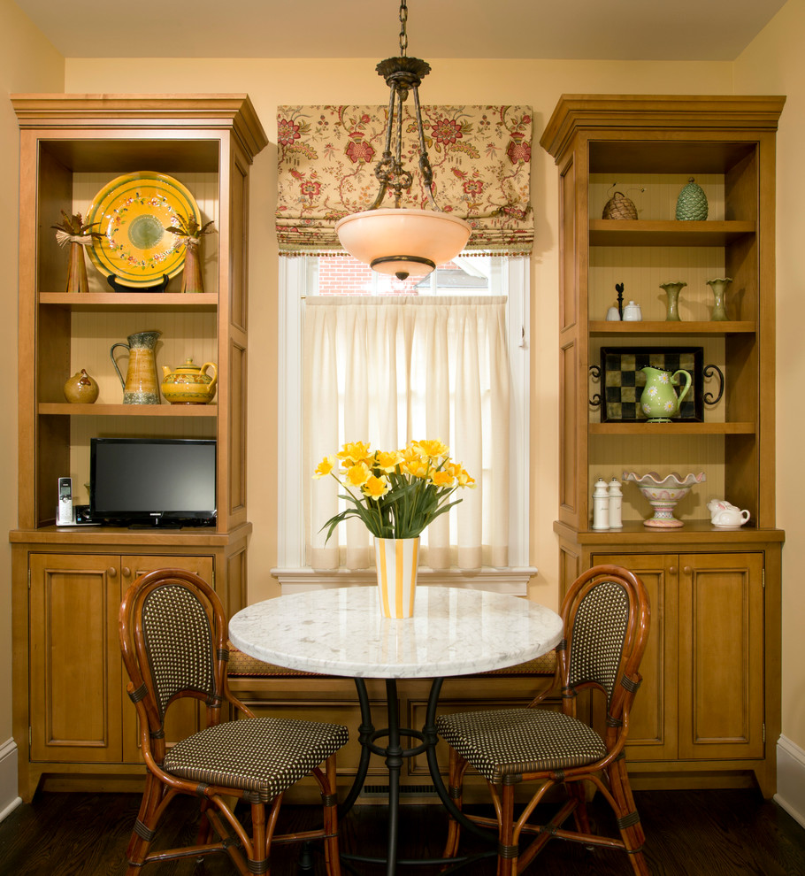 Inspiration pour une salle à manger traditionnelle avec un mur jaune et parquet foncé.