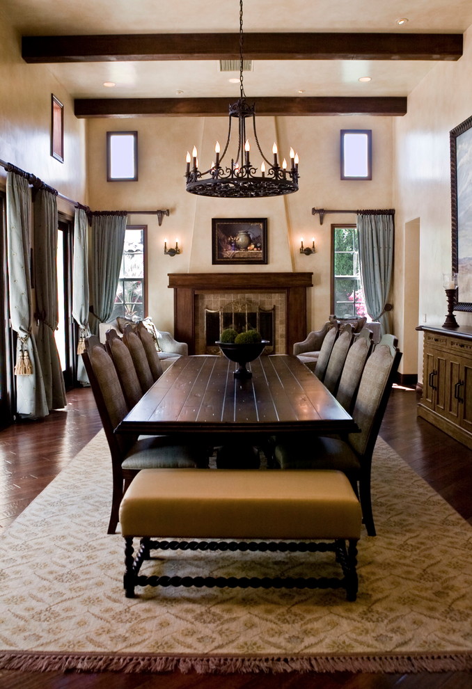 This is an example of a large mediterranean dining room in Los Angeles with dark hardwood flooring and a standard fireplace.