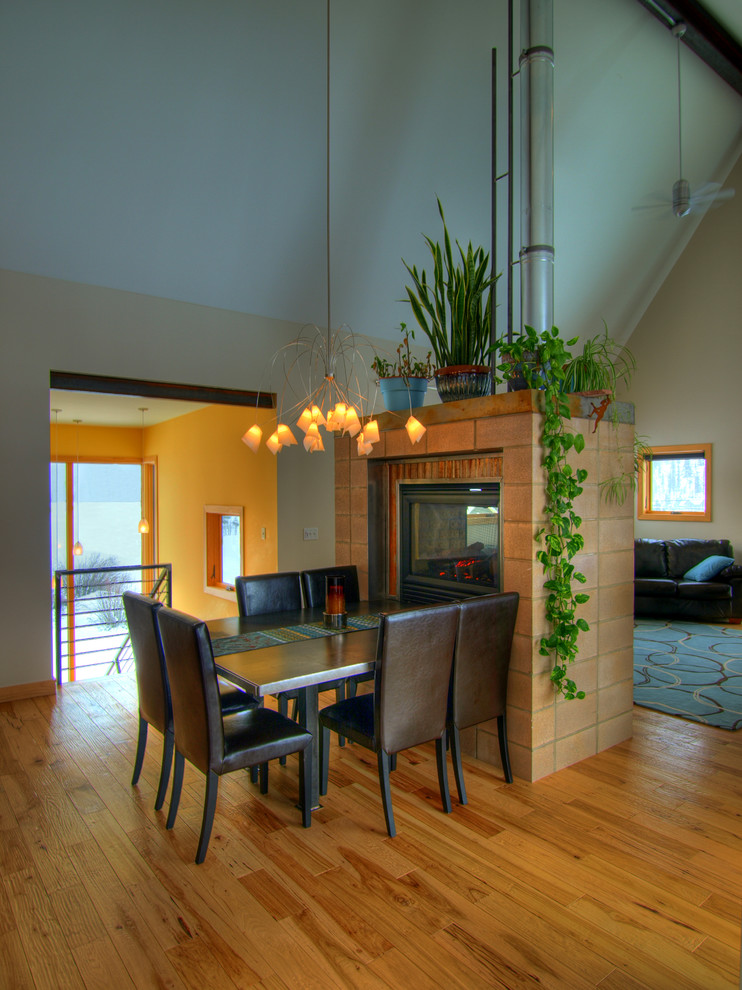 Kleine Moderne Wohnküche mit beiger Wandfarbe, hellem Holzboden, Tunnelkamin und Kaminumrandung aus Backstein in Phoenix