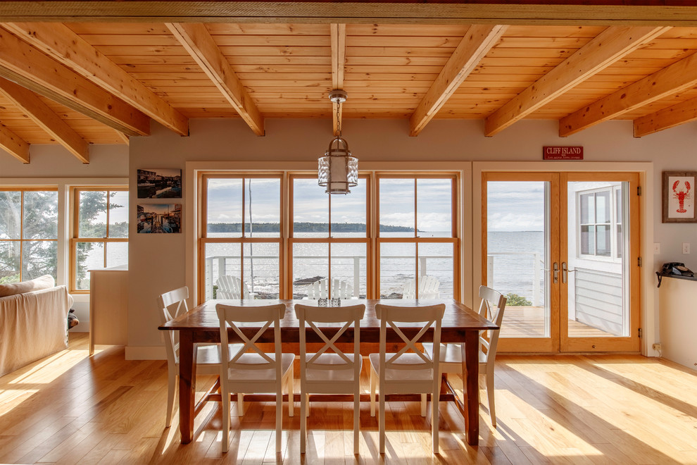 Immagine di una sala da pranzo aperta verso il soggiorno costiera di medie dimensioni con pareti bianche e parquet chiaro