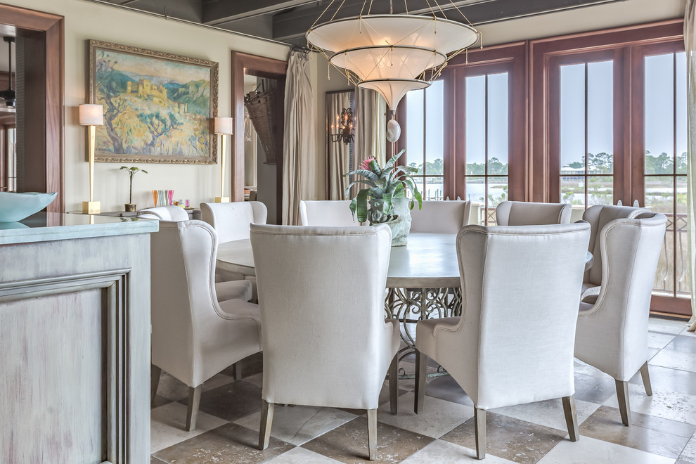 Immagine di un'ampia sala da pranzo aperta verso il soggiorno tropicale con pareti beige e pavimento in pietra calcarea