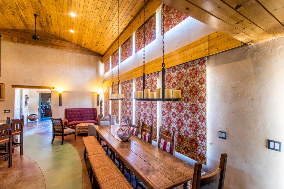 Inspiration pour une salle à manger ouverte sur la cuisine sud-ouest américain de taille moyenne avec un mur beige, sol en béton ciré, un poêle à bois, un manteau de cheminée en béton et un sol vert.