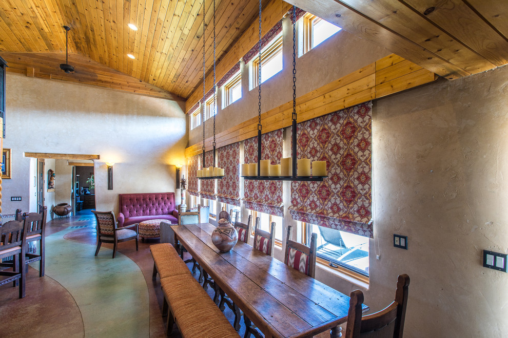 Idee per una sala da pranzo aperta verso la cucina american style di medie dimensioni con pareti beige, pavimento in cemento, stufa a legna, cornice del camino in cemento e pavimento verde