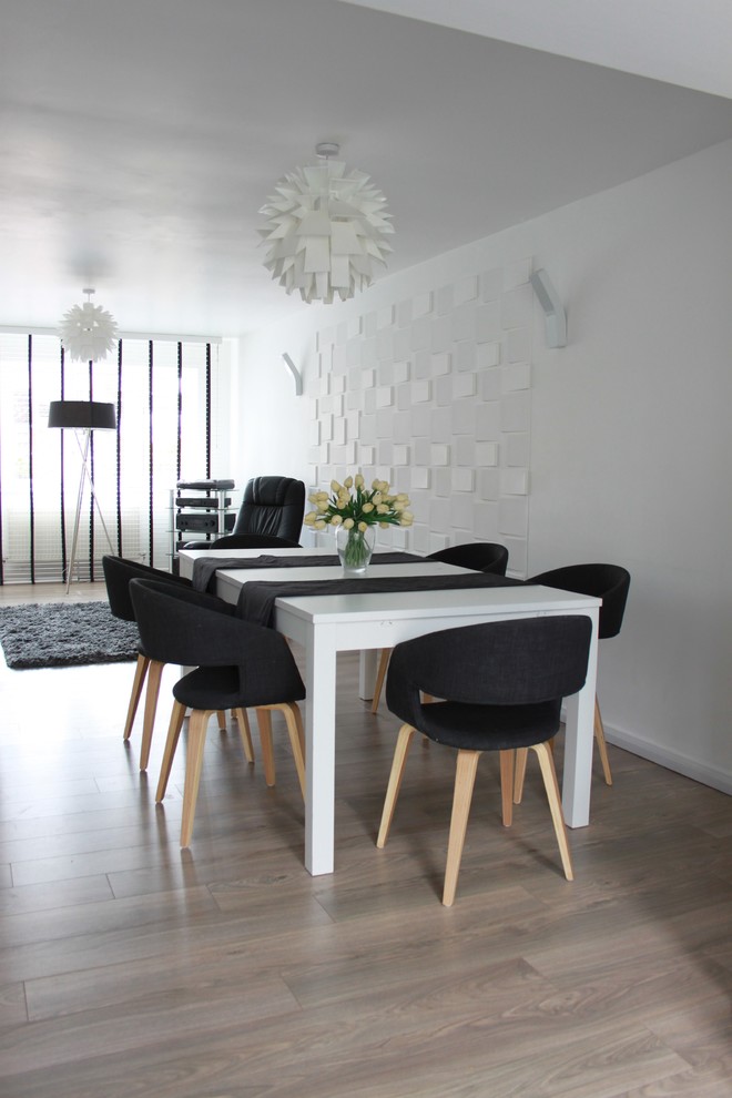 Immagine di una sala da pranzo aperta verso il soggiorno minimalista di medie dimensioni con pareti bianche, pavimento in compensato e nessun camino
