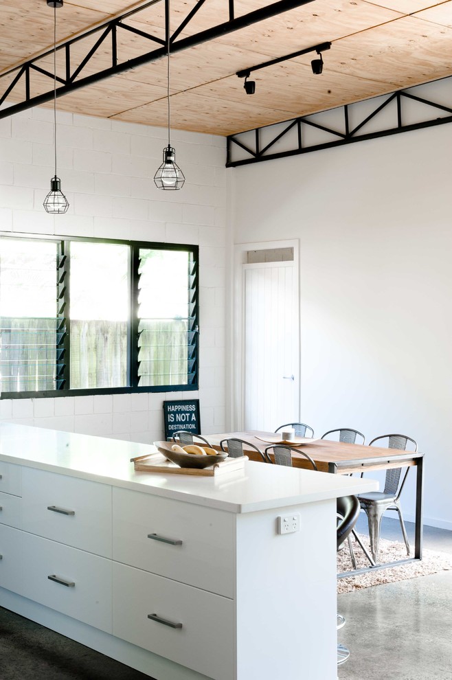 Cette photo montre une salle à manger ouverte sur le salon industrielle de taille moyenne avec un mur blanc et sol en béton ciré.