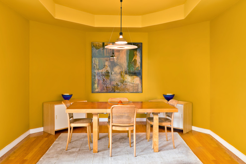 Aménagement d'une petite salle à manger contemporaine fermée avec un mur jaune, un sol en bois brun et aucune cheminée.