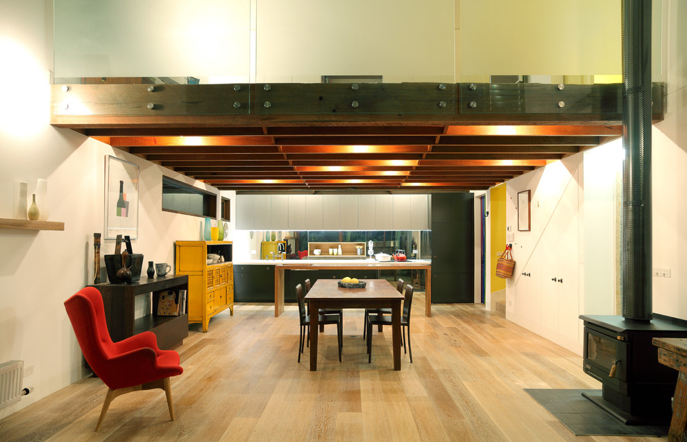 This is an example of a large open plan dining room in Melbourne with light hardwood flooring, a wood burning stove and a metal fireplace surround.