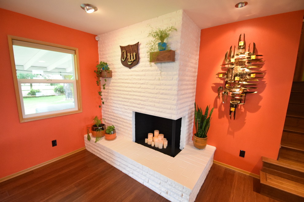 Пример оригинального дизайна: большая кухня-столовая в стиле ретро с оранжевыми стенами, полом из бамбука, угловым камином, фасадом камина из кирпича и коричневым полом