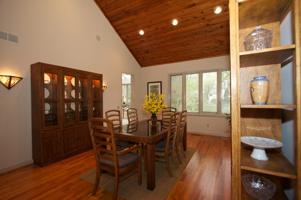 Cette photo montre une salle à manger éclectique avec un mur jaune et un sol en bois brun.