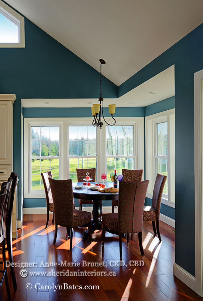 Cette image montre une salle à manger ouverte sur le salon traditionnelle avec un mur bleu et un sol en bois brun.