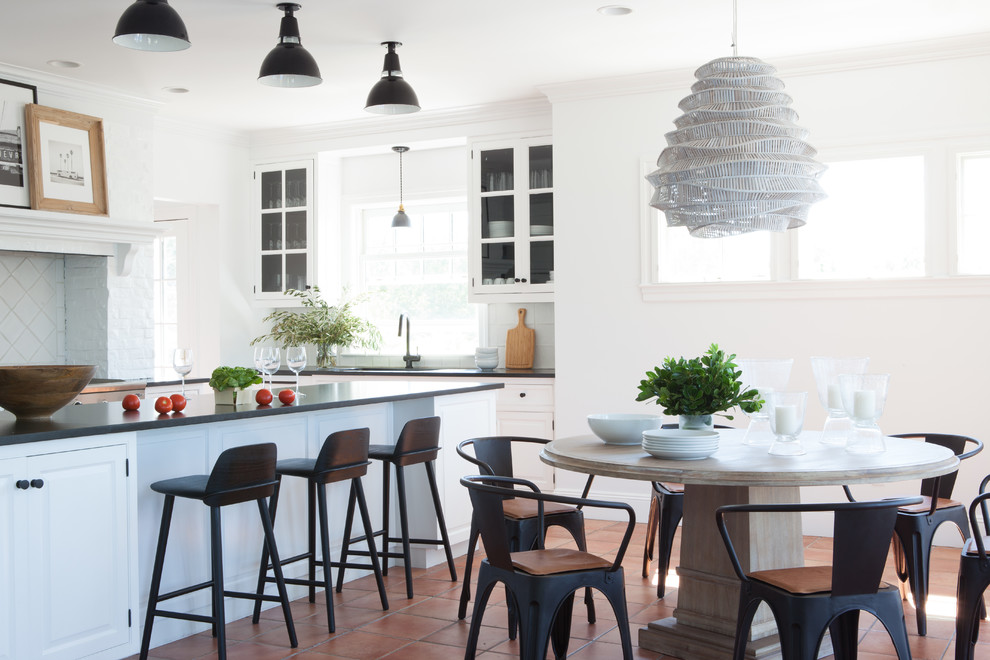 Foto di una sala da pranzo aperta verso la cucina stile marino con pareti bianche, pavimento in terracotta e pavimento marrone