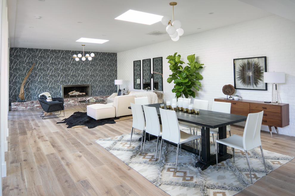 Large retro open plan dining room in San Francisco with light hardwood flooring, a standard fireplace, a concrete fireplace surround and white floors.