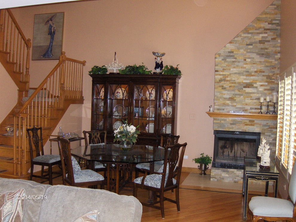 Inspiration pour une salle à manger ouverte sur la cuisine bohème de taille moyenne avec un mur orange, parquet foncé, une cheminée d'angle et un manteau de cheminée en pierre.