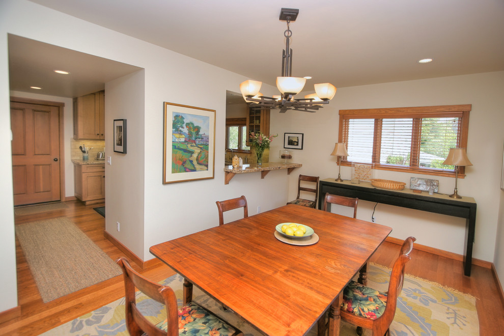 Example of a mid-sized classic medium tone wood floor enclosed dining room design in Santa Barbara with white walls