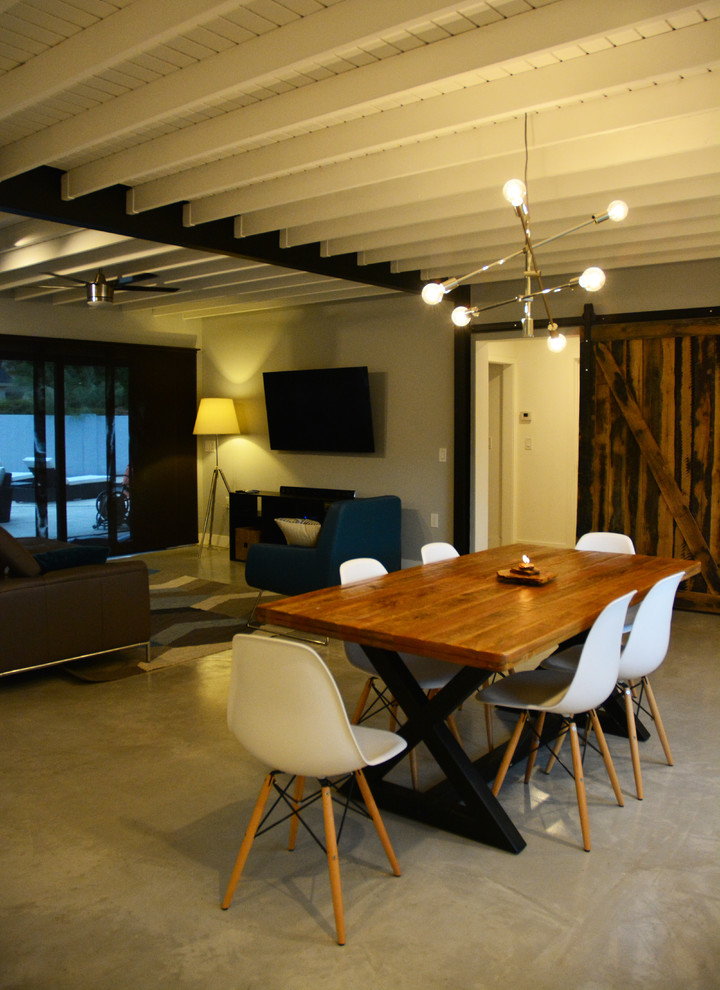Exemple d'une salle à manger ouverte sur le salon industrielle de taille moyenne avec un mur blanc, sol en béton ciré et aucune cheminée.