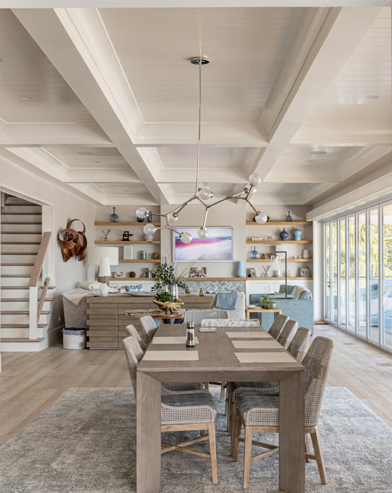 Immagine di una sala da pranzo aperta verso il soggiorno costiera con pareti grigie, parquet chiaro, pavimento beige e soffitto a cassettoni