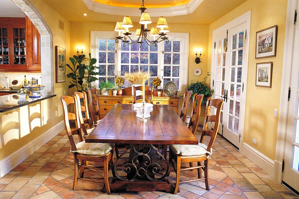 Стильный дизайн: кухня-столовая в классическом стиле с желтыми стенами и полом из терракотовой плитки - последний тренд