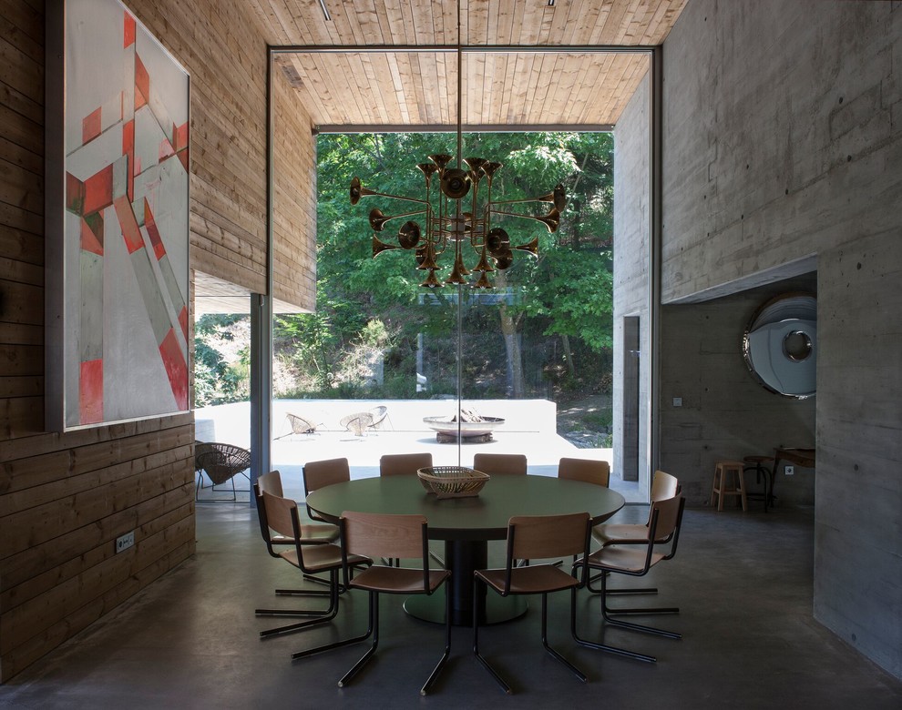 Aménagement d'une salle à manger contemporaine avec un mur gris, sol en béton ciré et un sol gris.
