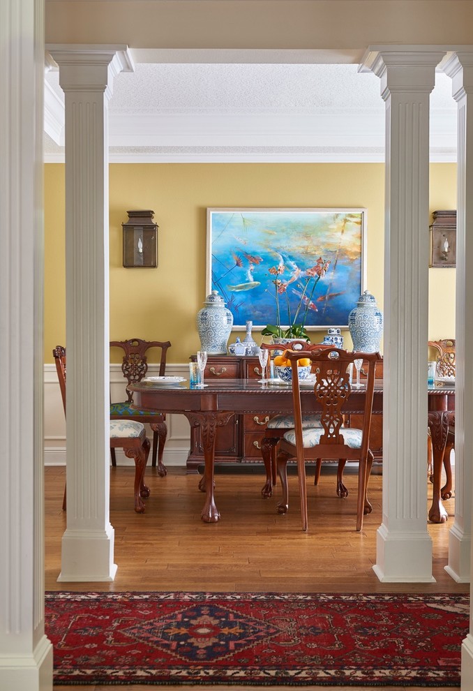 Cette photo montre une salle à manger éclectique fermée et de taille moyenne avec un mur jaune, un sol en bois brun et aucune cheminée.