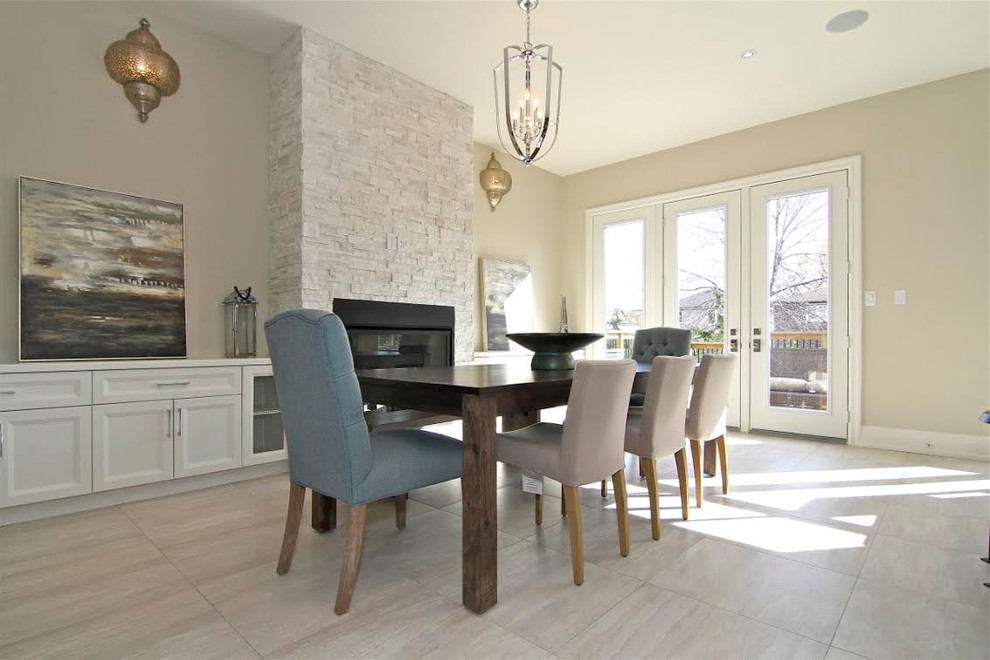 This is an example of a medium sized contemporary kitchen/dining room in Toronto with beige walls, travertine flooring, a standard fireplace, a stone fireplace surround and beige floors.