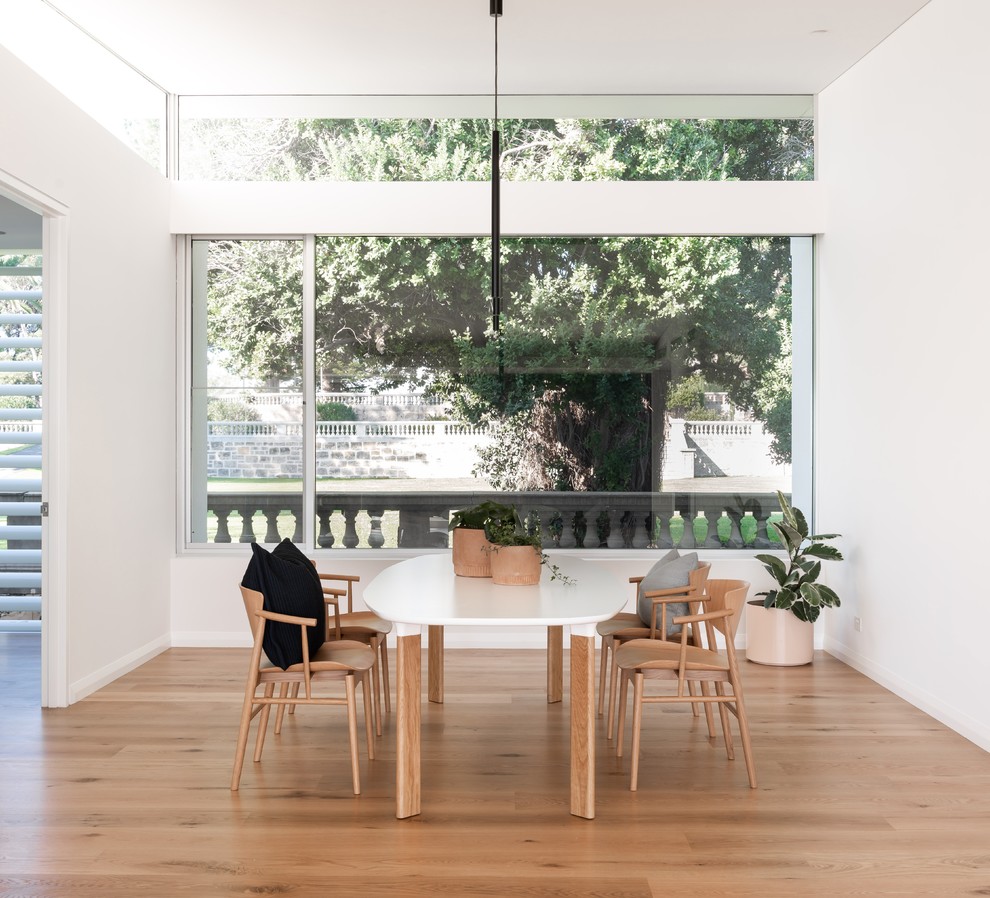 Idée de décoration pour une salle à manger minimaliste avec un mur blanc, un sol en bois brun et un sol marron.