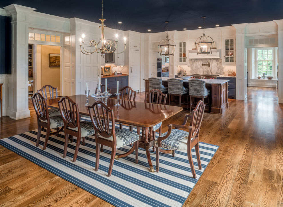 Immagine di una grande sala da pranzo aperta verso la cucina tradizionale con pareti blu, pavimento in legno massello medio e pavimento marrone