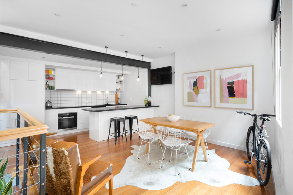 Photo of a small scandi kitchen/dining room in Melbourne with white walls, medium hardwood flooring and brown floors.